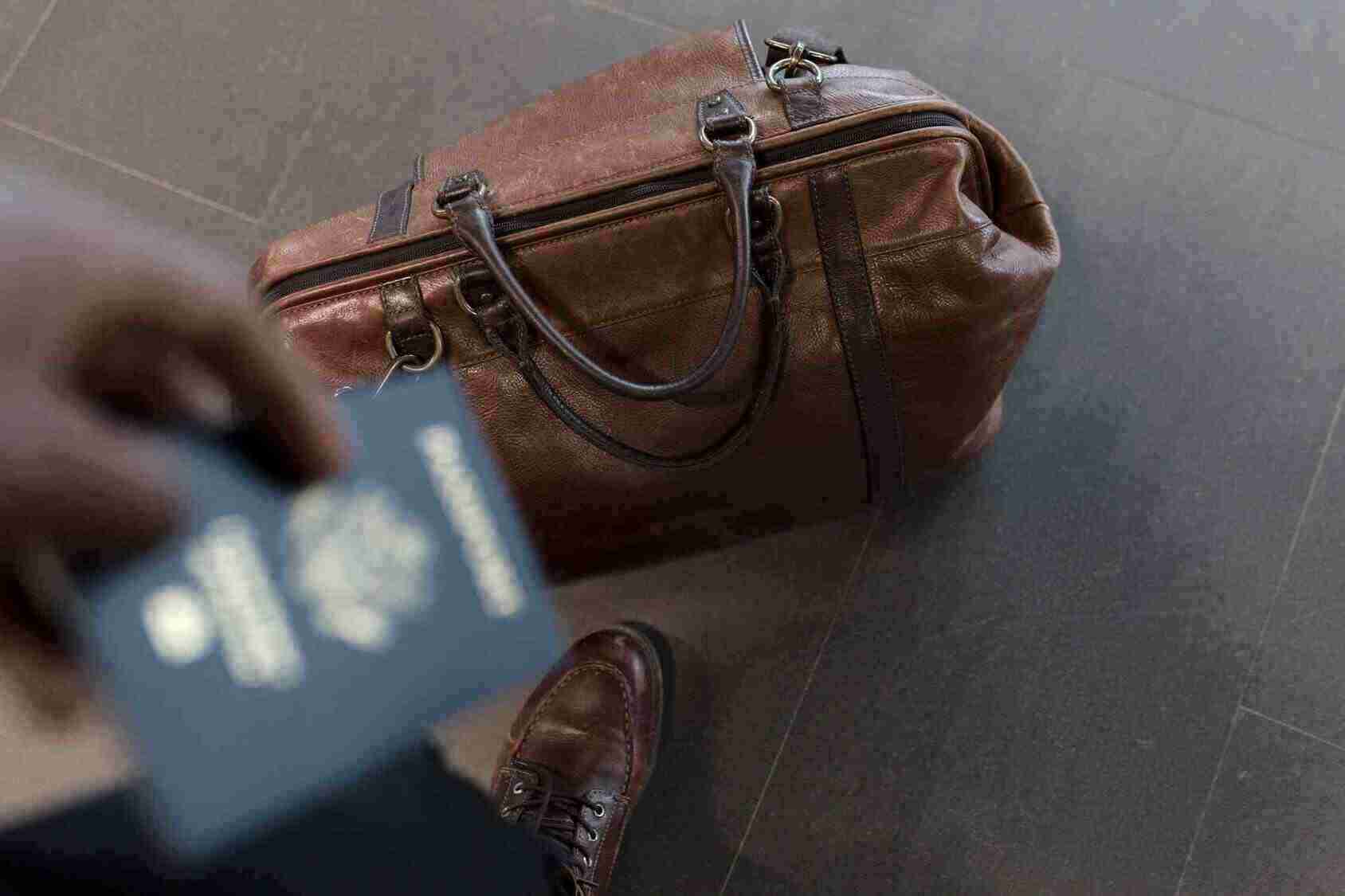 Osoba drži pasoš i putna torba